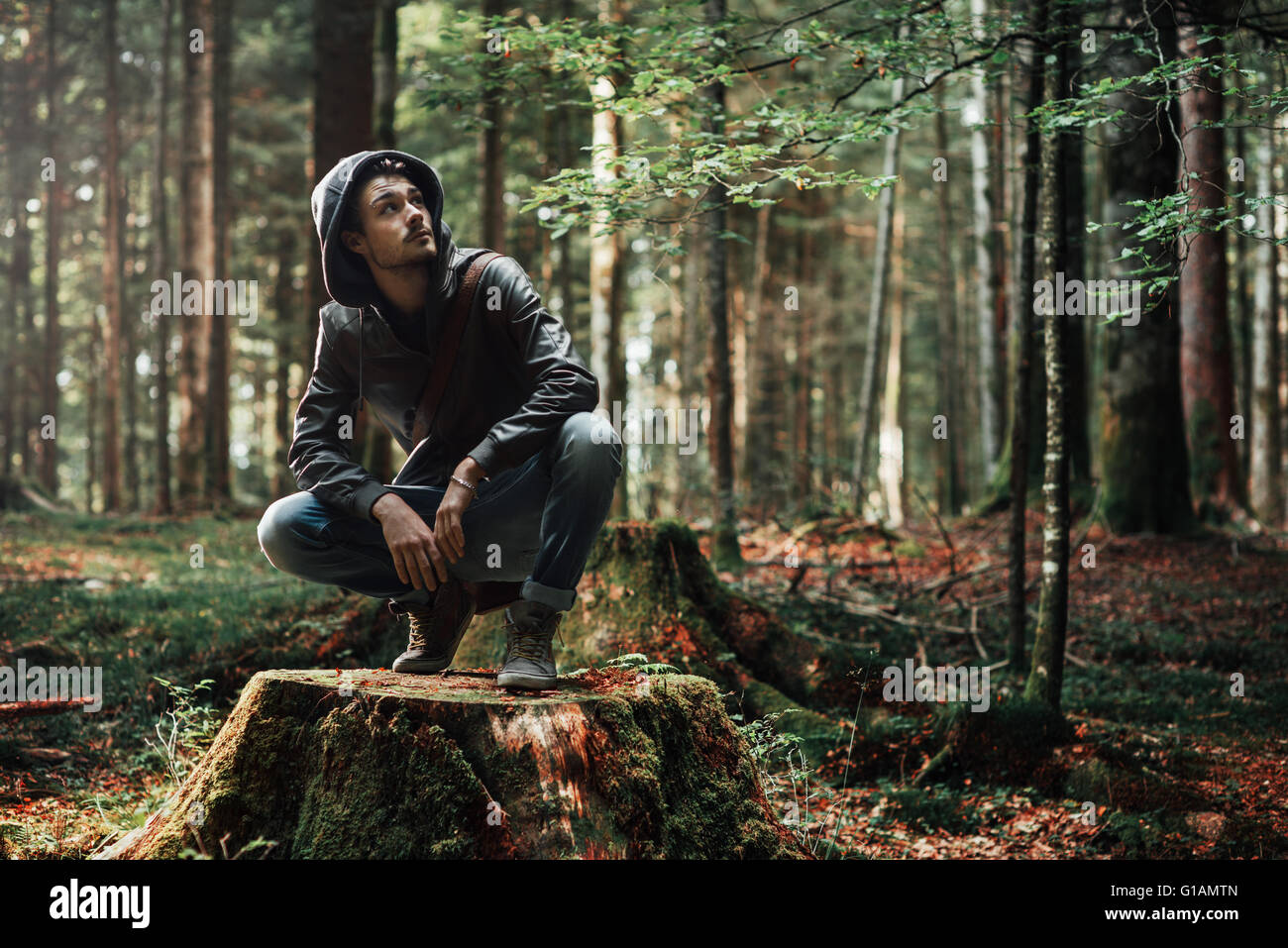 Giovane uomo bello esplorare la foresta e guardandosi attorno, della natura e del concetto di libertà Foto Stock