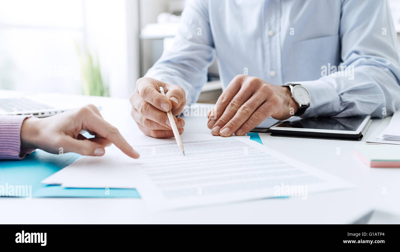 La gente di affari di negoziare un contratto, essi stanno puntando su un documento e discutendo insieme Foto Stock