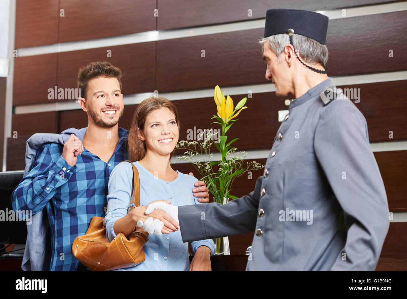 Concierge handshake dando al giovane in hotel come segno di benvenuto Foto Stock