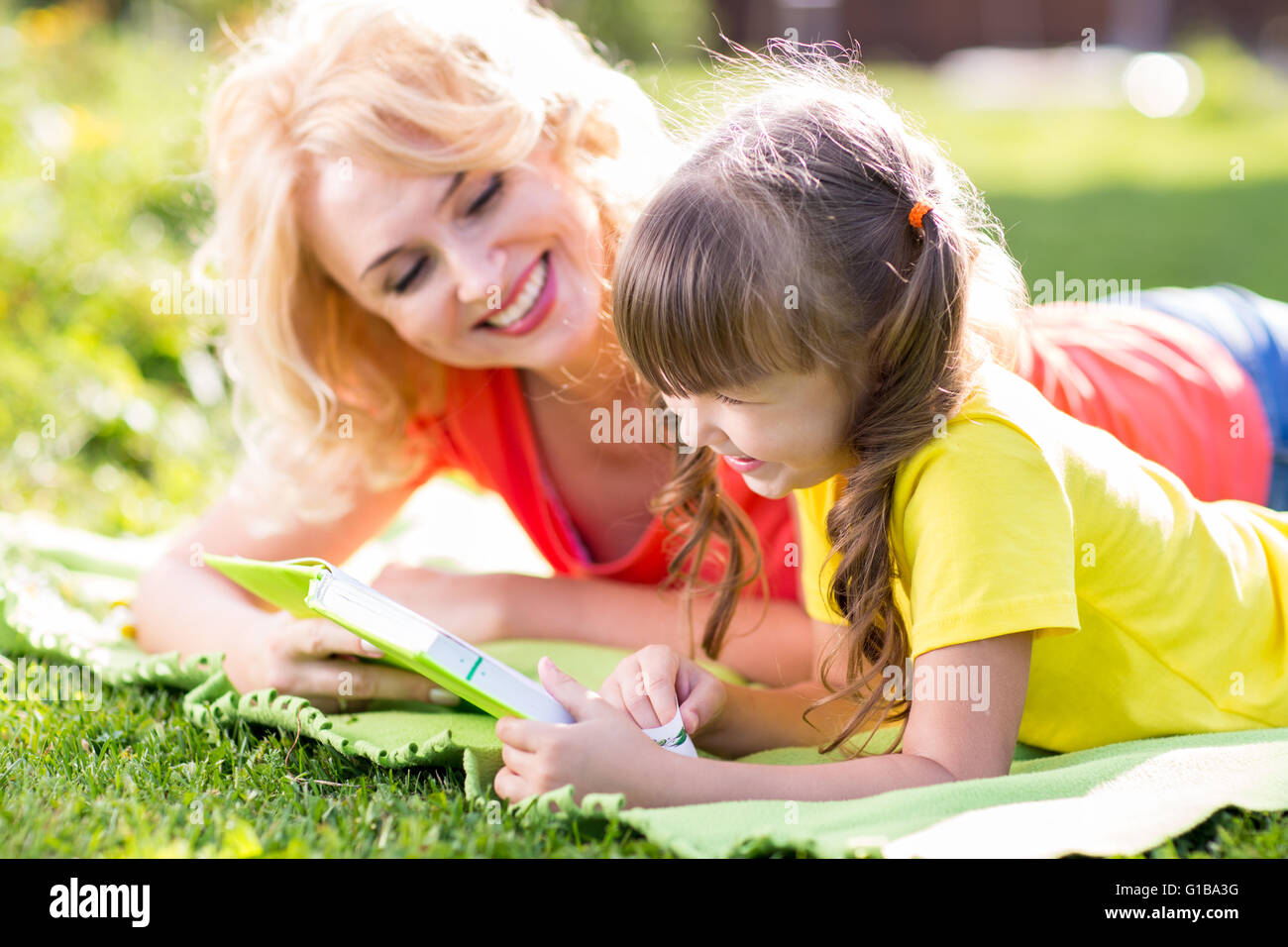 Madre con bambino figlia giacente in estate park Foto Stock