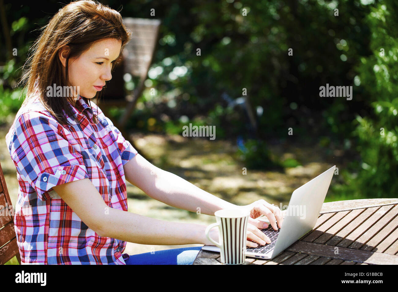 Ritratto di una donna al di fuori del lavoro su un computer portatile con una tazza di tè o caffè Foto Stock