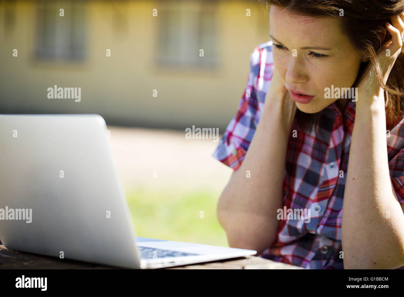 Ritratto di una donna al di fuori frustrato o arrabbiato con il suo computer portatile Foto Stock