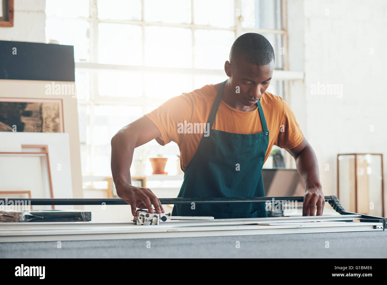 Giovani artigiani africani concentrandosi attentamente mentre utilizzando un utensile di lavoro con abilità e competenze in una incorniciatura workshop Foto Stock