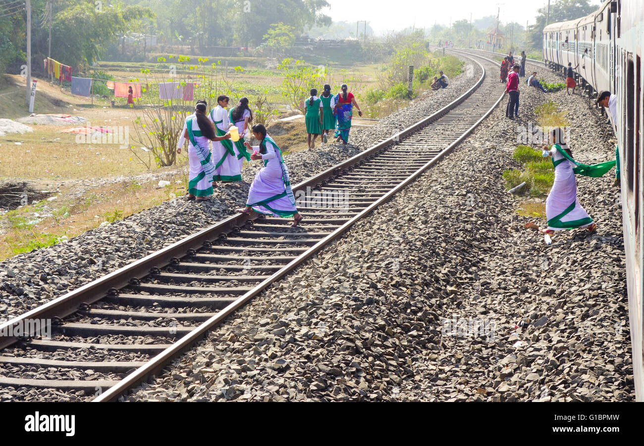 I giovani della scuola i bambini attraversare il binario ferroviario dopo scende da un treno nel Bengala occidentale, India Foto Stock