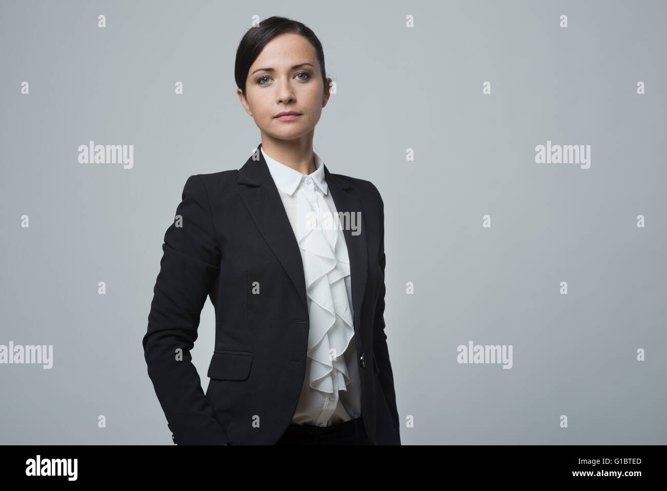 Fiducioso attraente imprenditrice che posano con le mani nelle tasche. Foto Stock