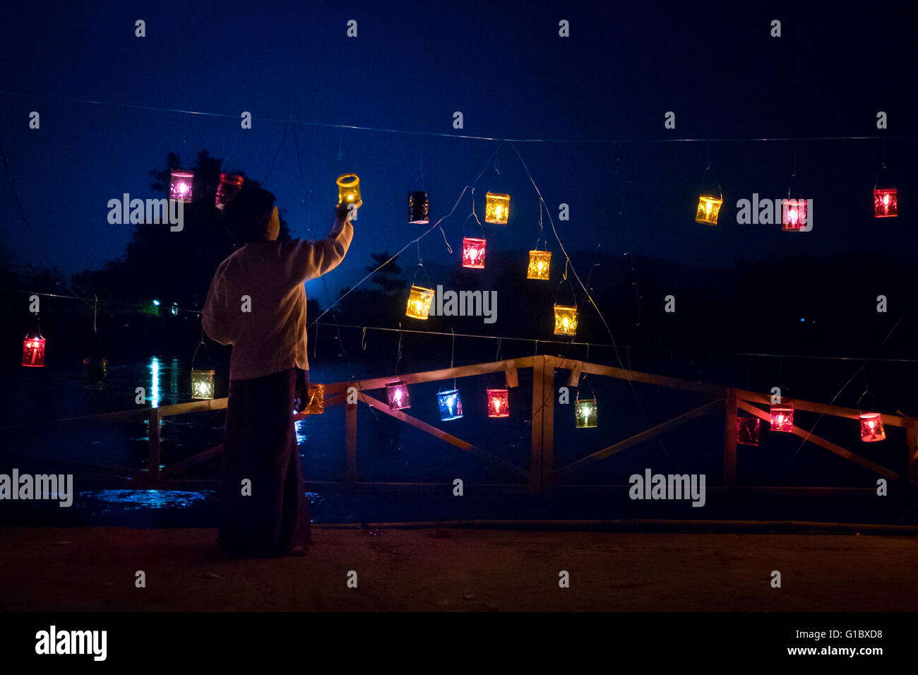 Un giovane ragazzo accendendo candele lungo il fiume in Hsipaw durante il "Festival Thidingyut. Il festival si terrà durante la luna piena alla fine di ottobre e segna il giorno Signore Buddha è disceso dal cielo dopo aver trascorso tre mesi della quaresima buddista. Il Buddha di ritorno è apprezzato in Myanmar con colorate luminarie e persone rilasciando i fuochi d'artificio e lanterne in cielo. Foto Stock