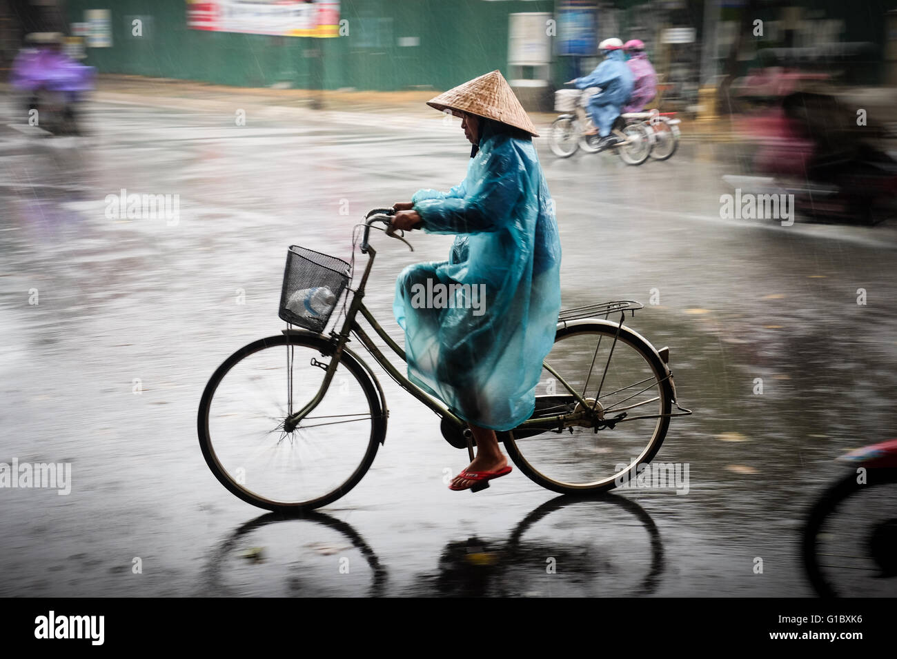 Una signora braves il wet weather in tinta, Vietnam Foto Stock