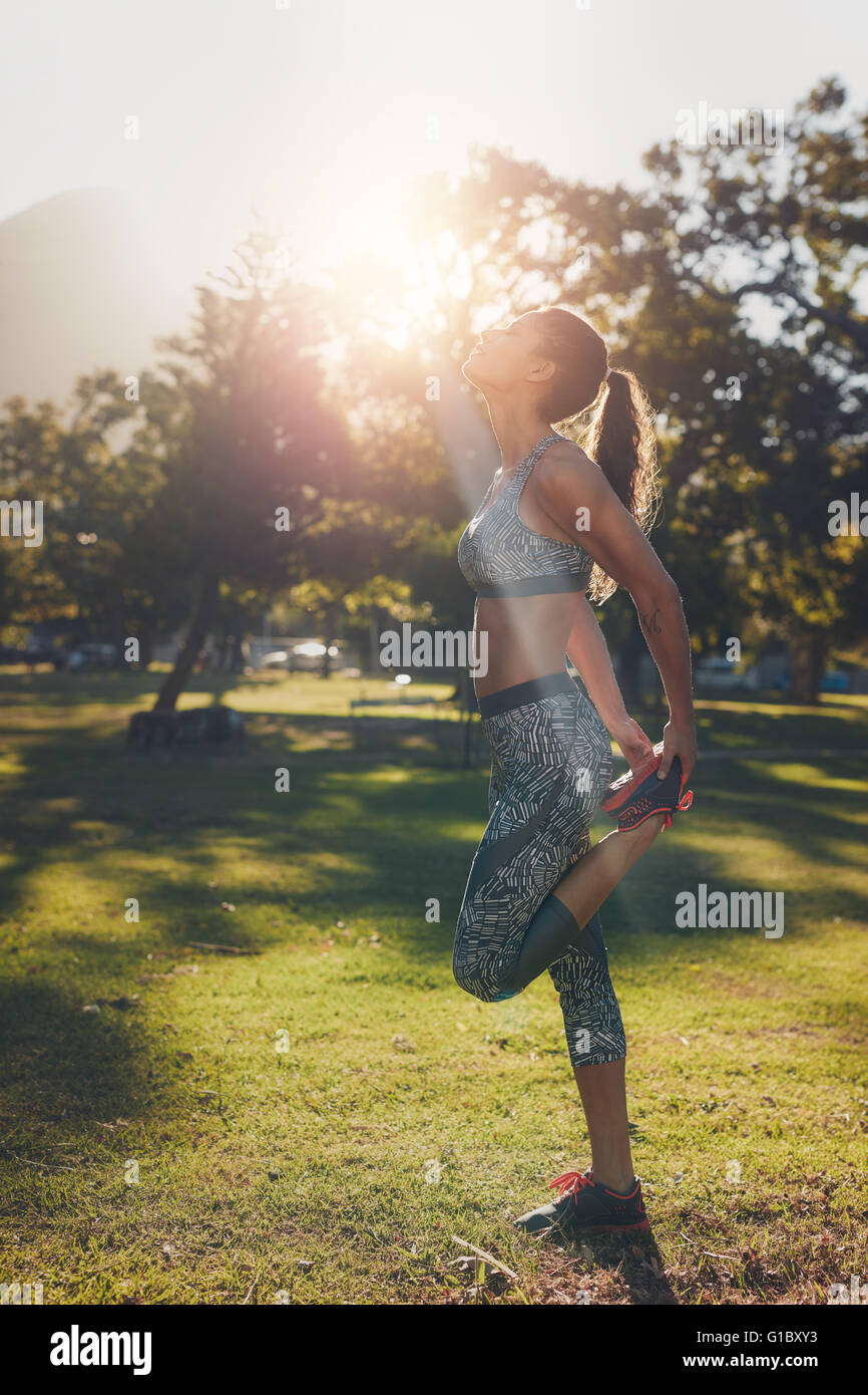Colpo all'aperto di montare la giovane donna in sportswear stretching le gambe prima di correre. Atleta femminile avvertenza fino e tenetevi pronti per Foto Stock