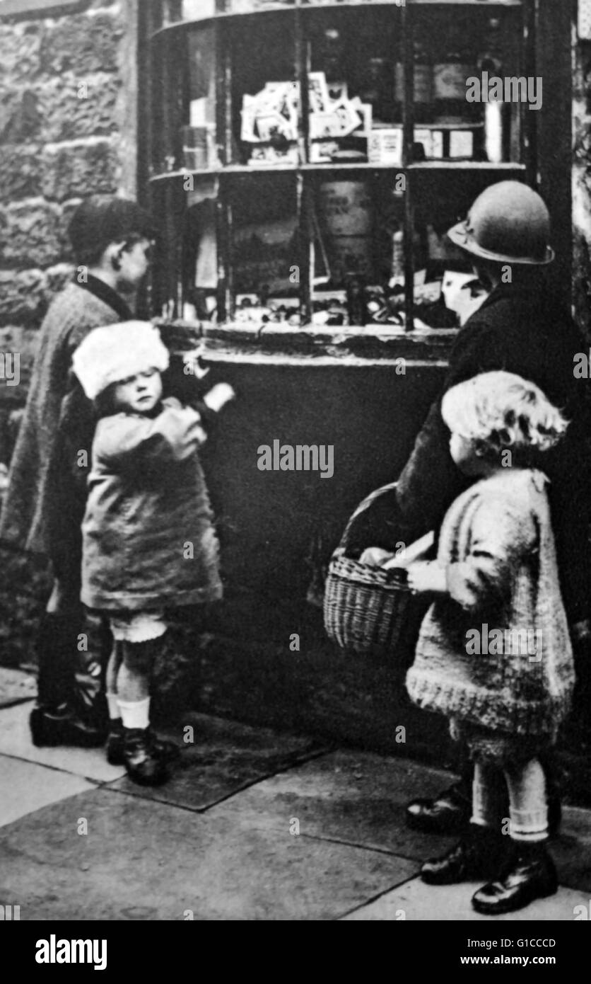 Degli anni trenta bambini si riuniscono al di fuori di un negozio di dolci; Inghilterra Foto Stock