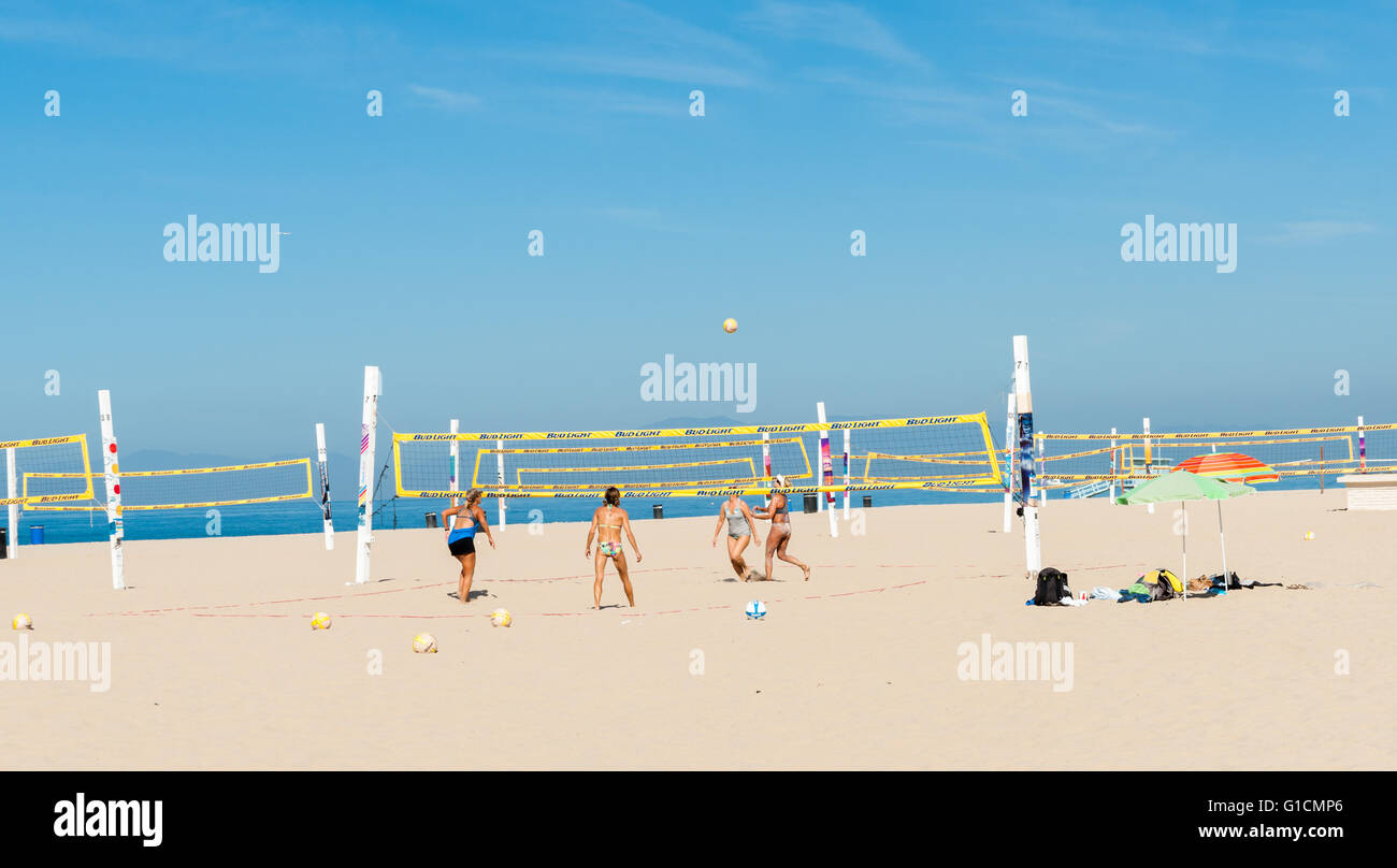 Donne conciate e montare a giocare a beach volley sotto californiano cielo estivo su Hermosa Beach Foto Stock