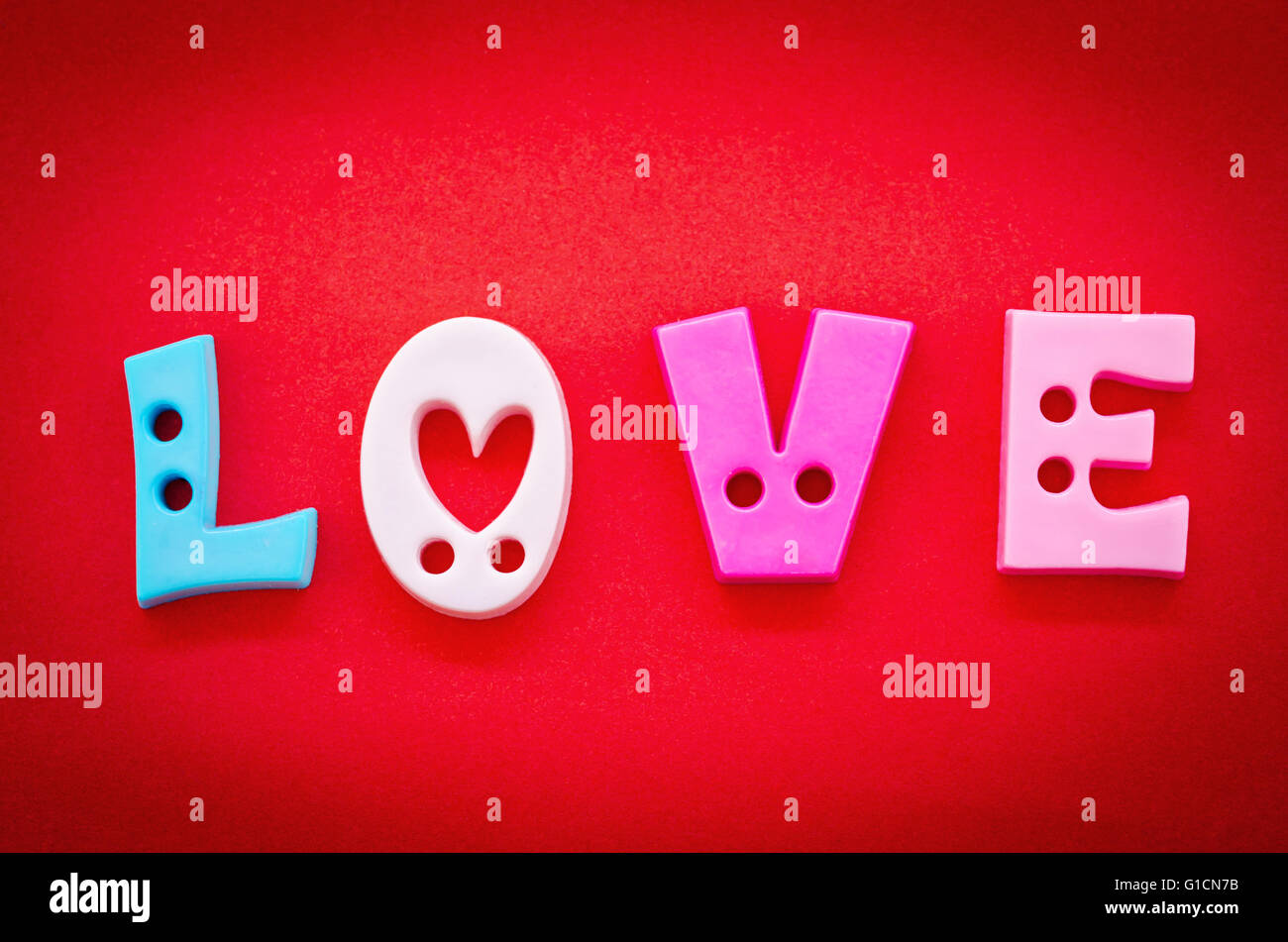 La parola amore, in lettere alfabeto su uno sfondo rosso per San Valentino, Natale, Pasqua, un compleanno o la festa della mamma. Foto Stock