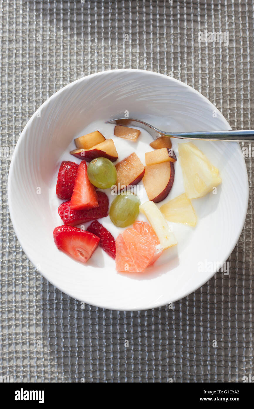 Sana colazione di ciotola di miscugli di frutta e yogurt con cucchiaio presi da un angolo alto. Foto Stock