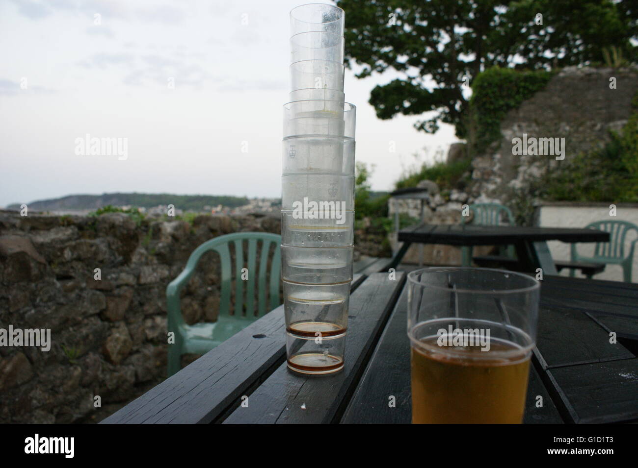 La pinta di birra e bicchieri vuoti la pinzatura di un massimo sul tavolo, outdoor presso un cucciolo, nei pressi della spiaggia in Galles Foto Stock