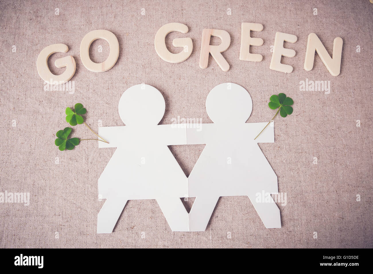 Le bambole di carta tenendo le mani con foglie verdi e "Go Green" parola Foto Stock