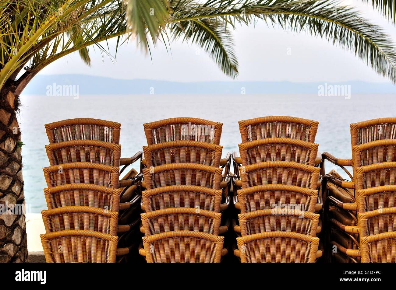 Sedie impilate sotto il palm tree in spiaggia Foto Stock