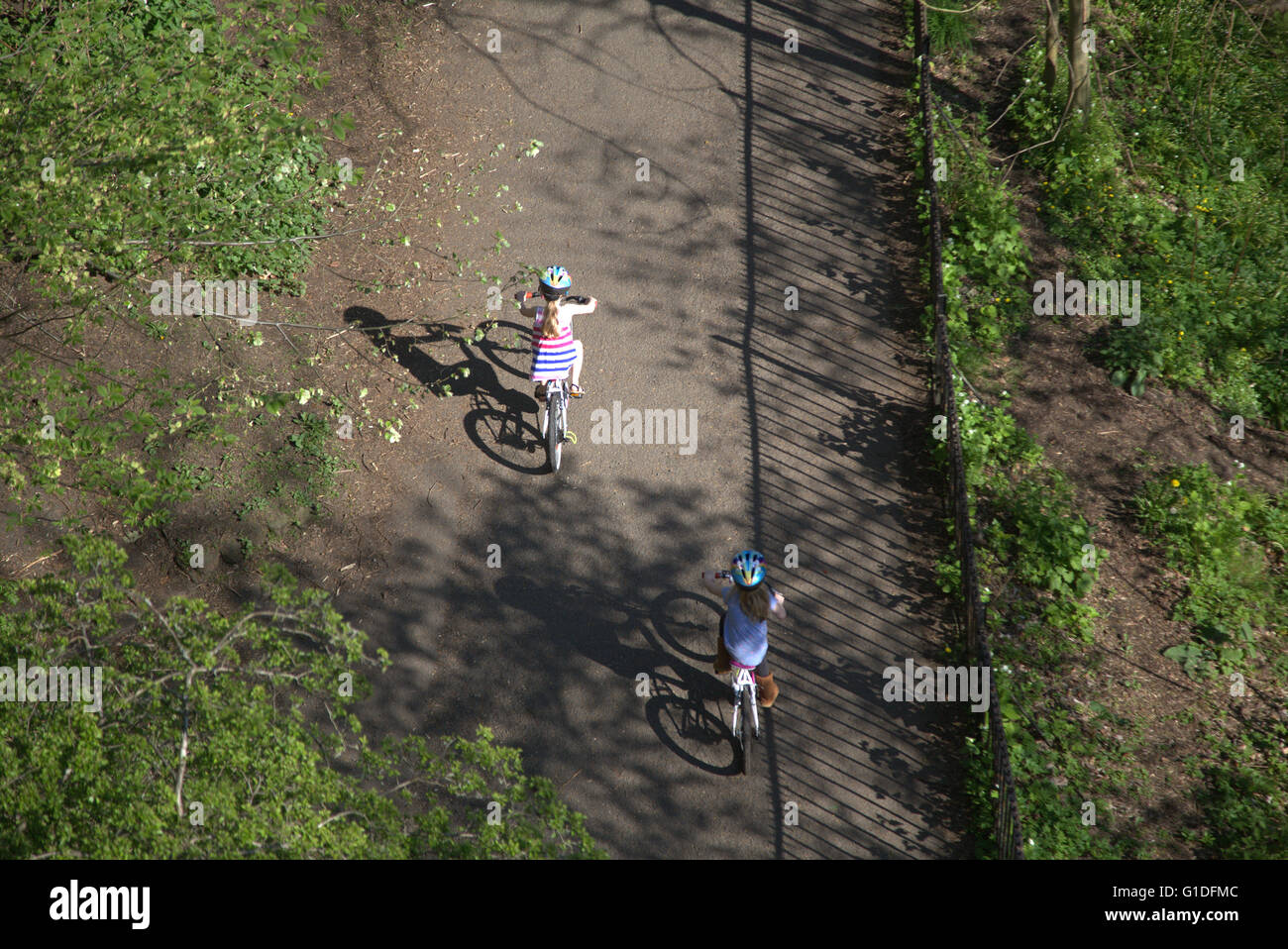Due bambine bambini su biciclette biciclette Kelvingrove Park shot dal di sopra in una giornata di sole, Kelvingrove Park, Foto Stock