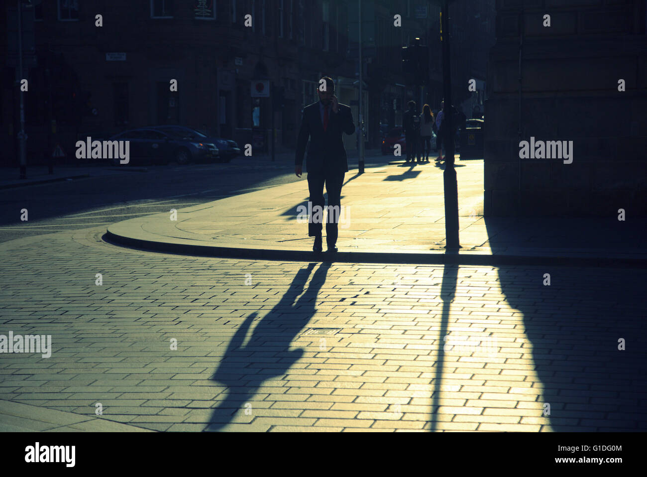 Silhouette di un uomo con ombra sulla strada di Glasgow con road cont- jour retroilluminato in Glasgow, Scotland, Regno Unito. Foto Stock