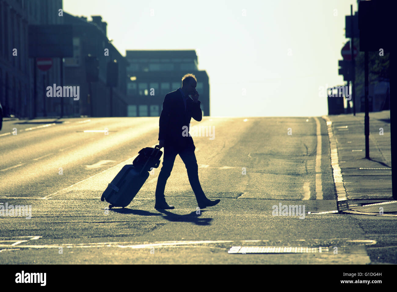 Silhouette ofman con i sacchetti in strada di Glasgow con road contre-jour retro-illuminato in Glasgow, Scotland, Regno Unito. Foto Stock