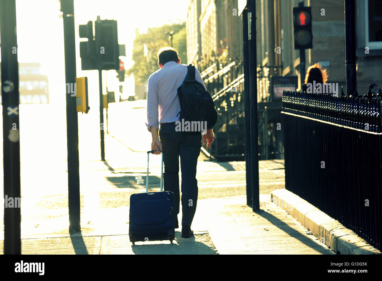 Silhouette di uomini con la sacca sulla strada di Glasgow con road contre-jour retro-illuminato in Glasgow, Scotland, Regno Unito. Foto Stock