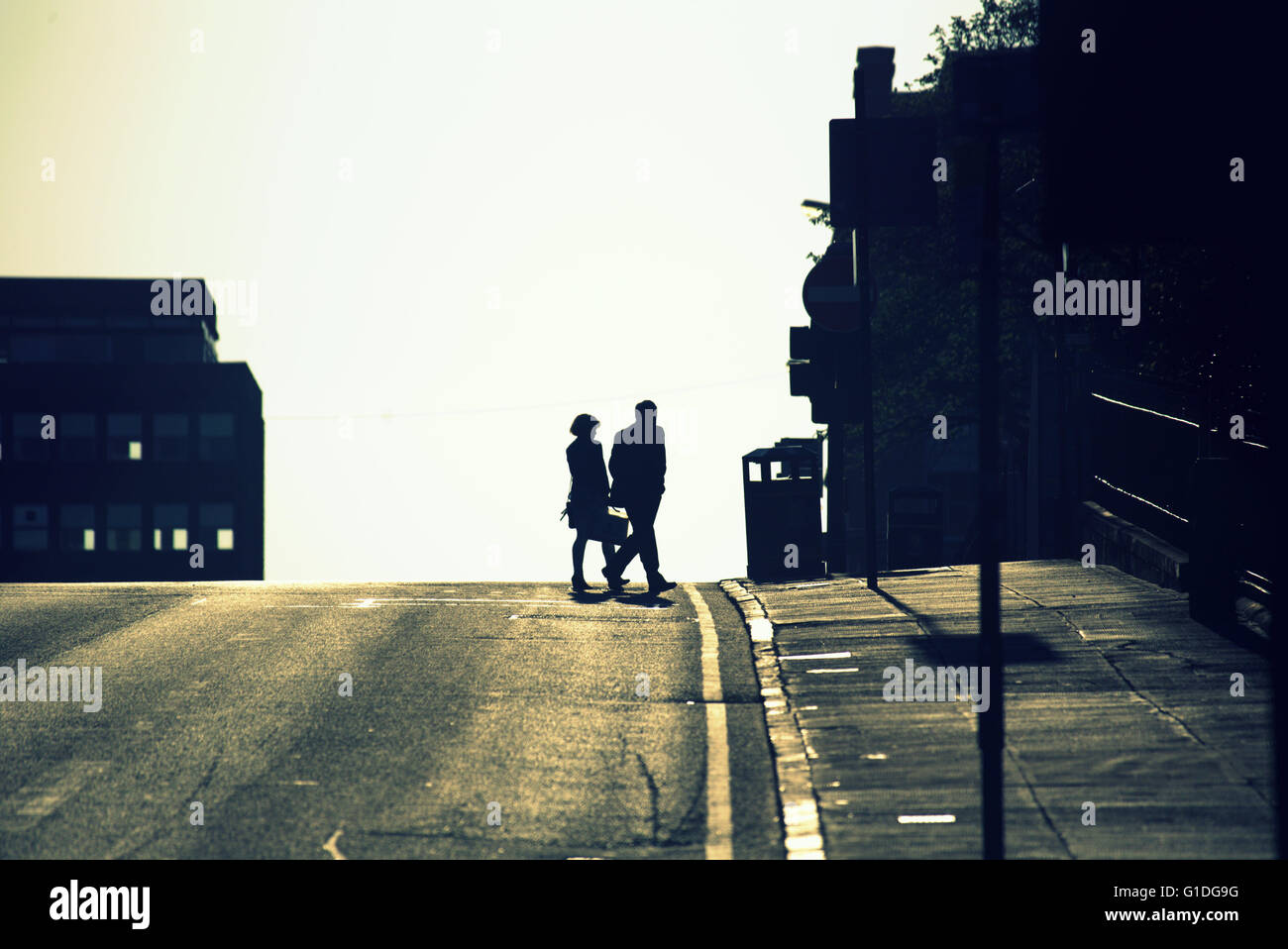 Silhouette di due persone una coppia sulla strada di Glasgow con road contre-jour retroilluminato in Glasgow, Scotland, Regno Unito. Foto Stock