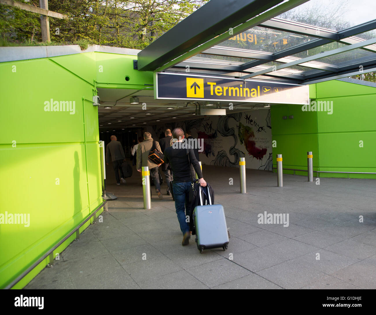 I passeggeri con bagagli camminare nel tunnel terminale, Londra Stansted, Essex, Inghilterra, Regno Unito Foto Stock