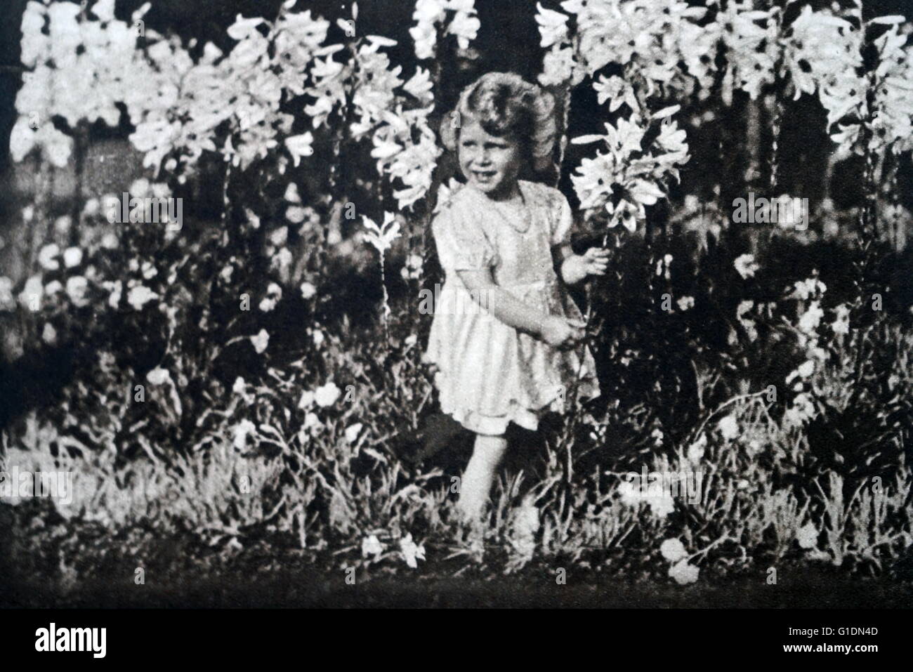 Fotografia di una giovane principessa Elisabetta (1926-) la sorella della Principessa Margaret (1930-2002) e futura Regina, giocando tra fiori. In data xx secolo Foto Stock