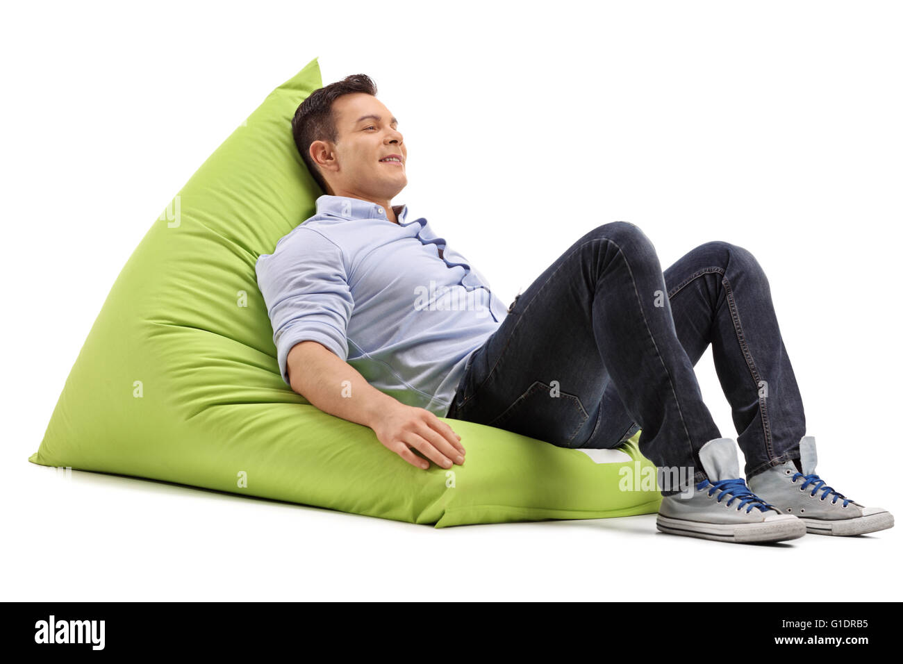 Rilassata giovane ragazzo seduto su un morbido e confortevole beanbag verde isolato su sfondo bianco Foto Stock