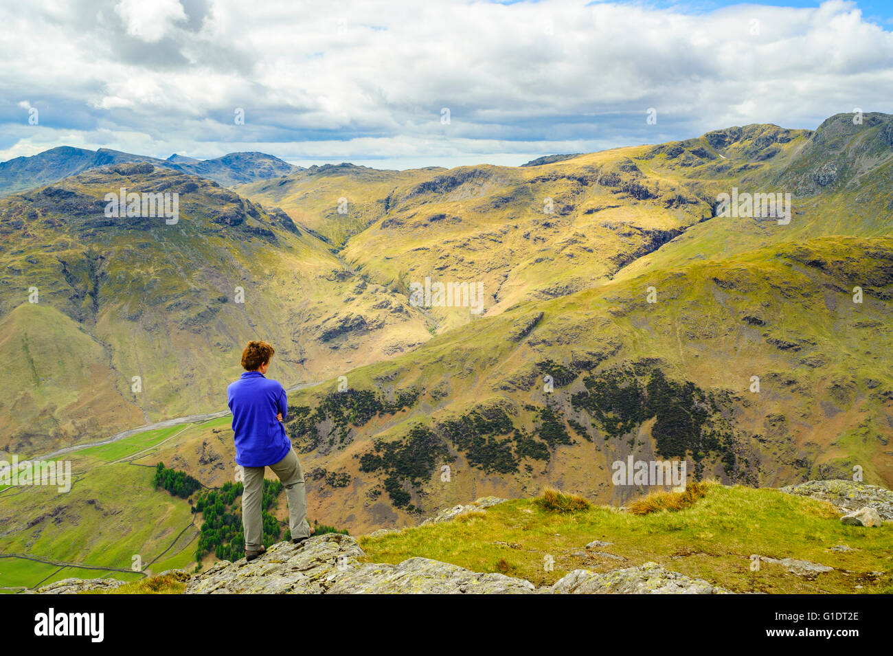 Walker su Pike o'Stickle uno di The Langdale Pikes nel distretto del lago guardando verso il Coniston Fells e balze ondulata Foto Stock