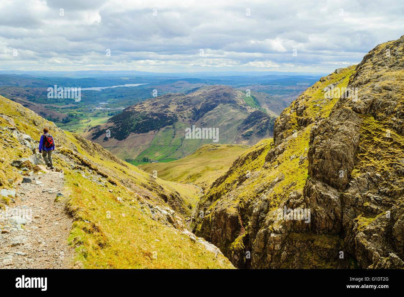 Walker sul percorso sopra Dungeon Ghyll su pendii di Harrison Stickle uno di The Langdale Pikes con distante Windermere Lake District Foto Stock