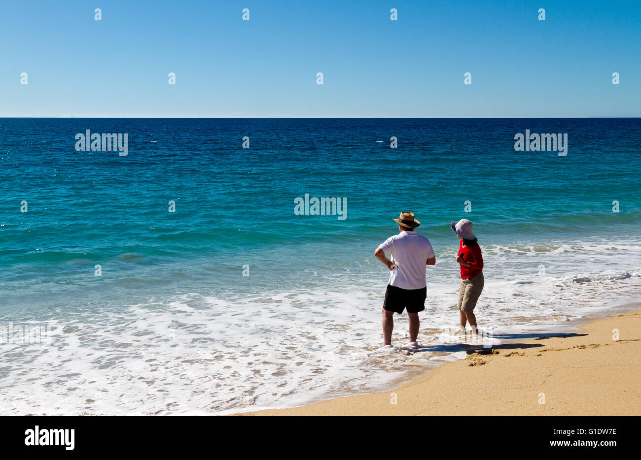Giovane guadare in oceano e tenendo nella vista a Las Palmas spiaggia vicino a Todos Santos, Baja California Sur, Messico. Foto Stock