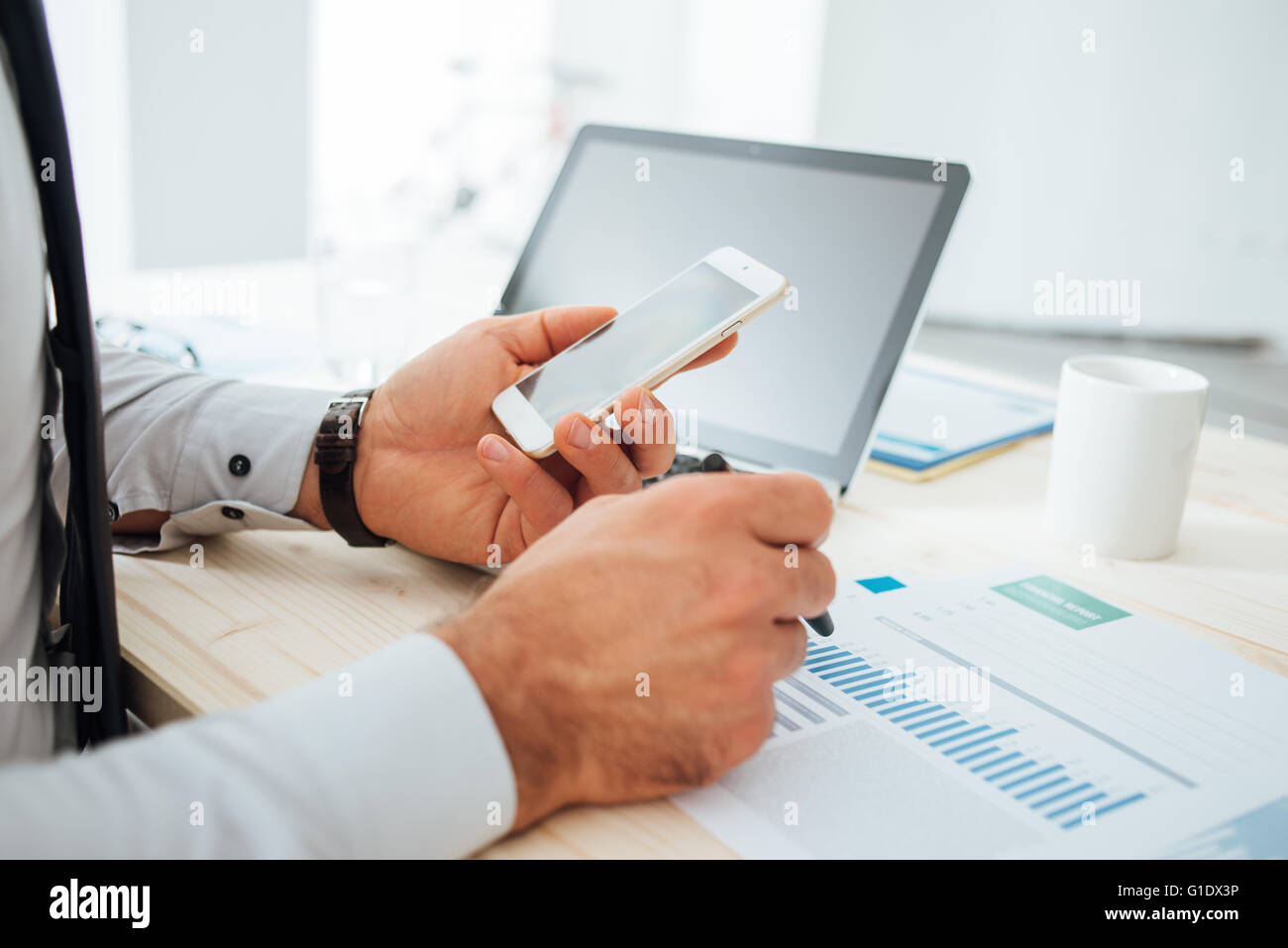Imprenditore al desk utilizzando un'applicazione finanziaria sul suo smart phone e lavorare sulle relazioni e le mani vicino fino Foto Stock