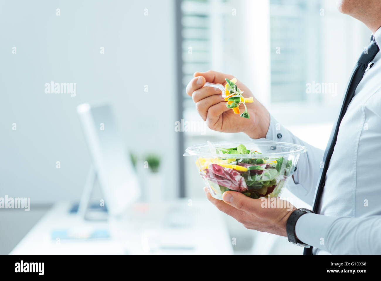 Imprenditore avente un insalata di verdure per pranzo, sana alimentazione e corretto stile di vita concetto, irriconoscibile persona Foto Stock
