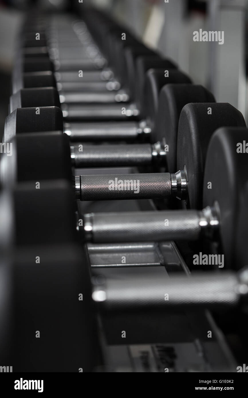Righe di nuovi pesi nella palestra, sulla cremagliera Foto Stock