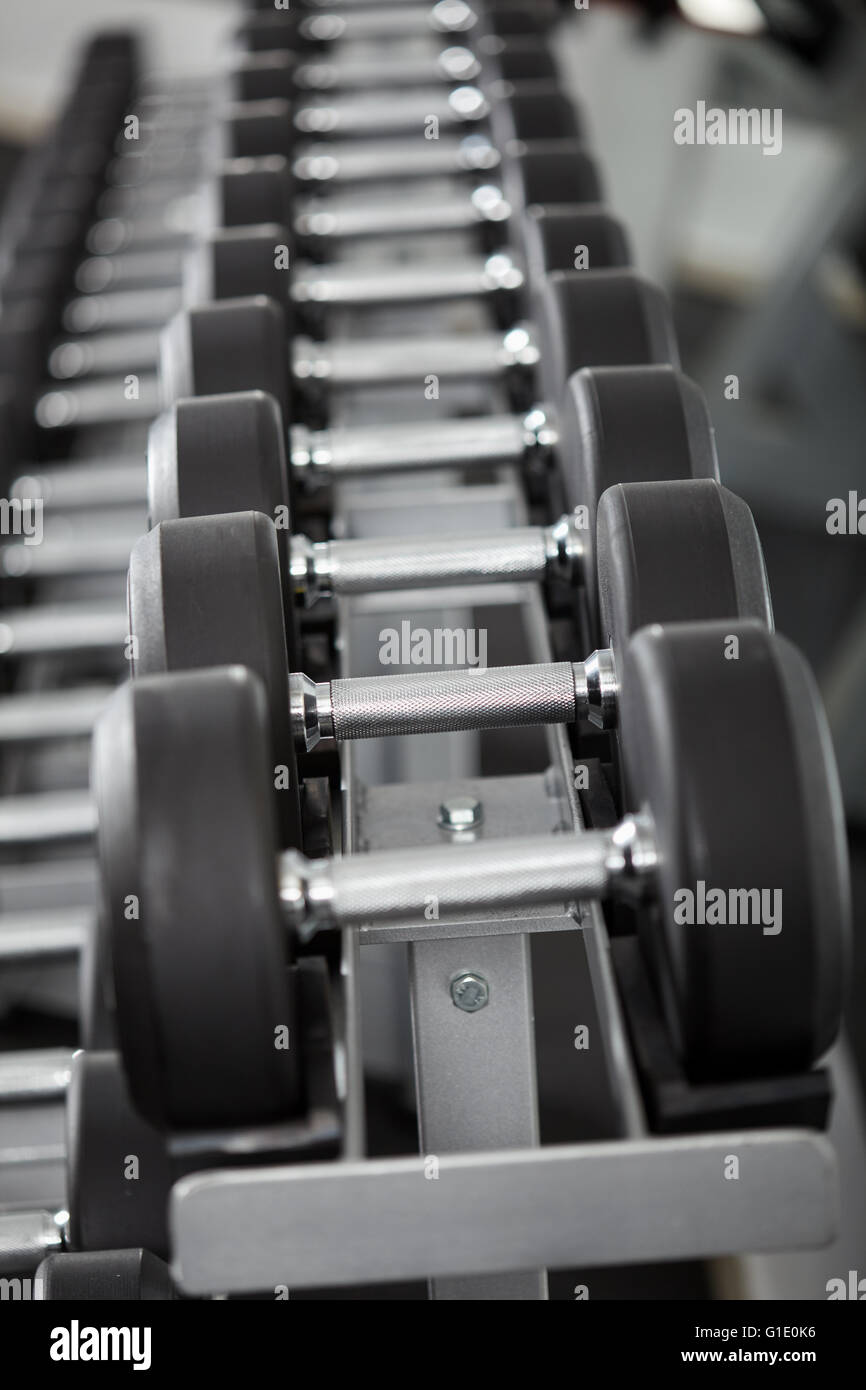Righe di nuovi pesi nella palestra, sulla cremagliera Foto Stock