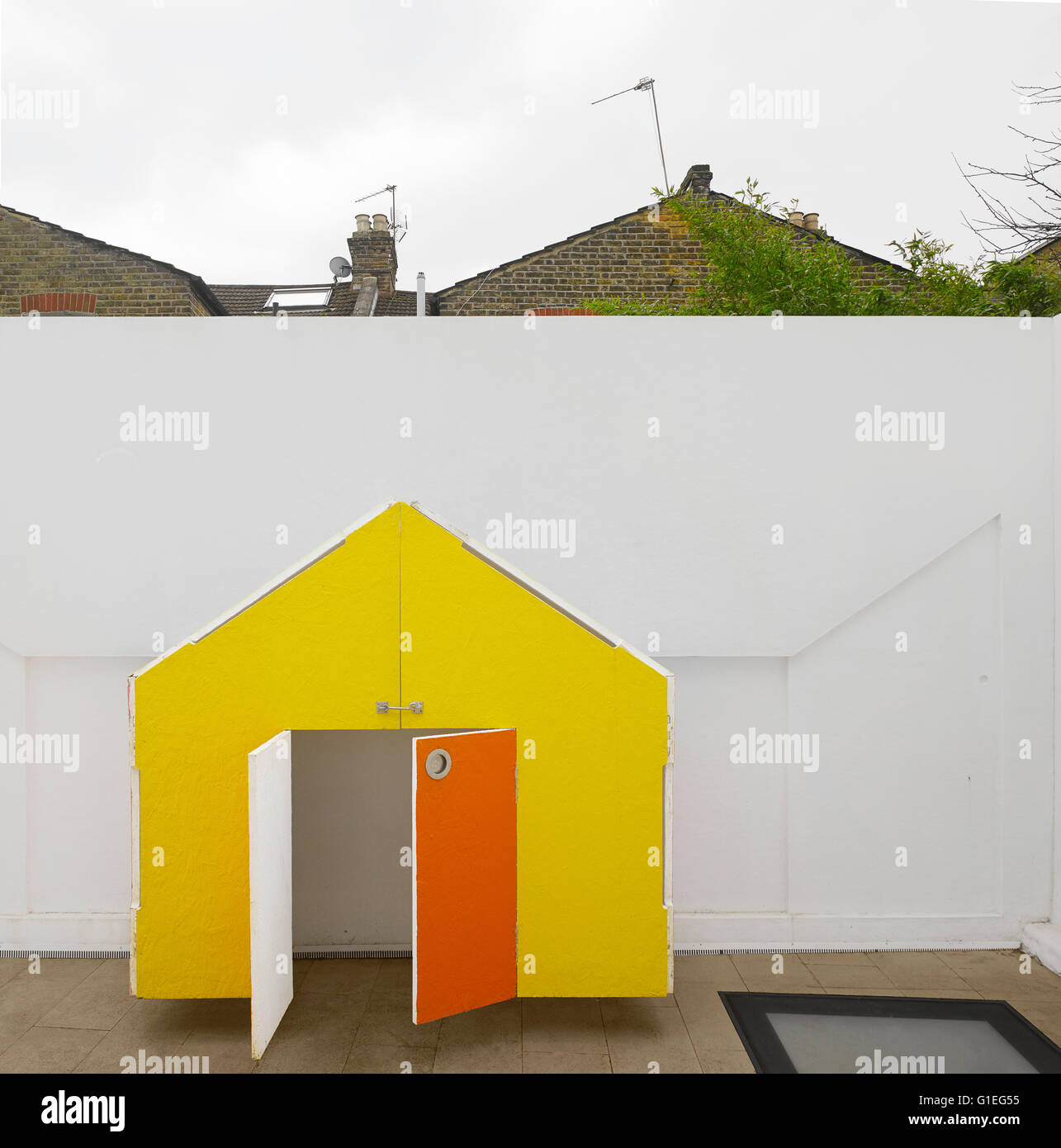 Famiglia moderna home, Shepherds Bush, Londra. Chiudere la vista di un giallo wendy house con porte arancione. Foto Stock