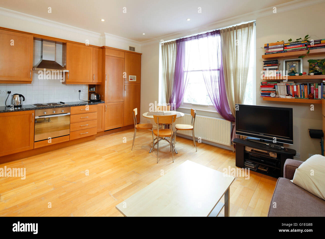 Belsize Lane, Hampstead. Salotto a pianta aperta e una cucina con pavimenti in legno e grandi finestre. Foto Stock