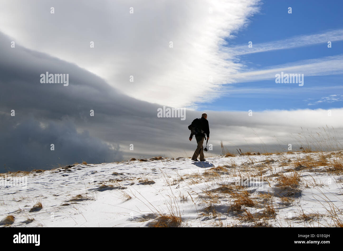 Uomo in una montagna innevata, cambiando rapidamente meteo, una tempesta è in arrivo Foto Stock
