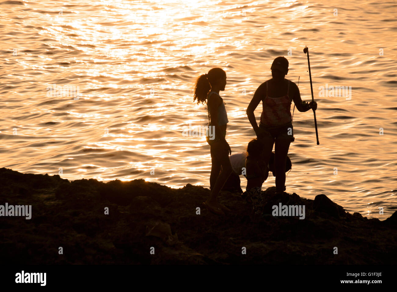 Persone di pesca al tramonto sotto il Malecon sea wall, Havana, Cuba Foto Stock