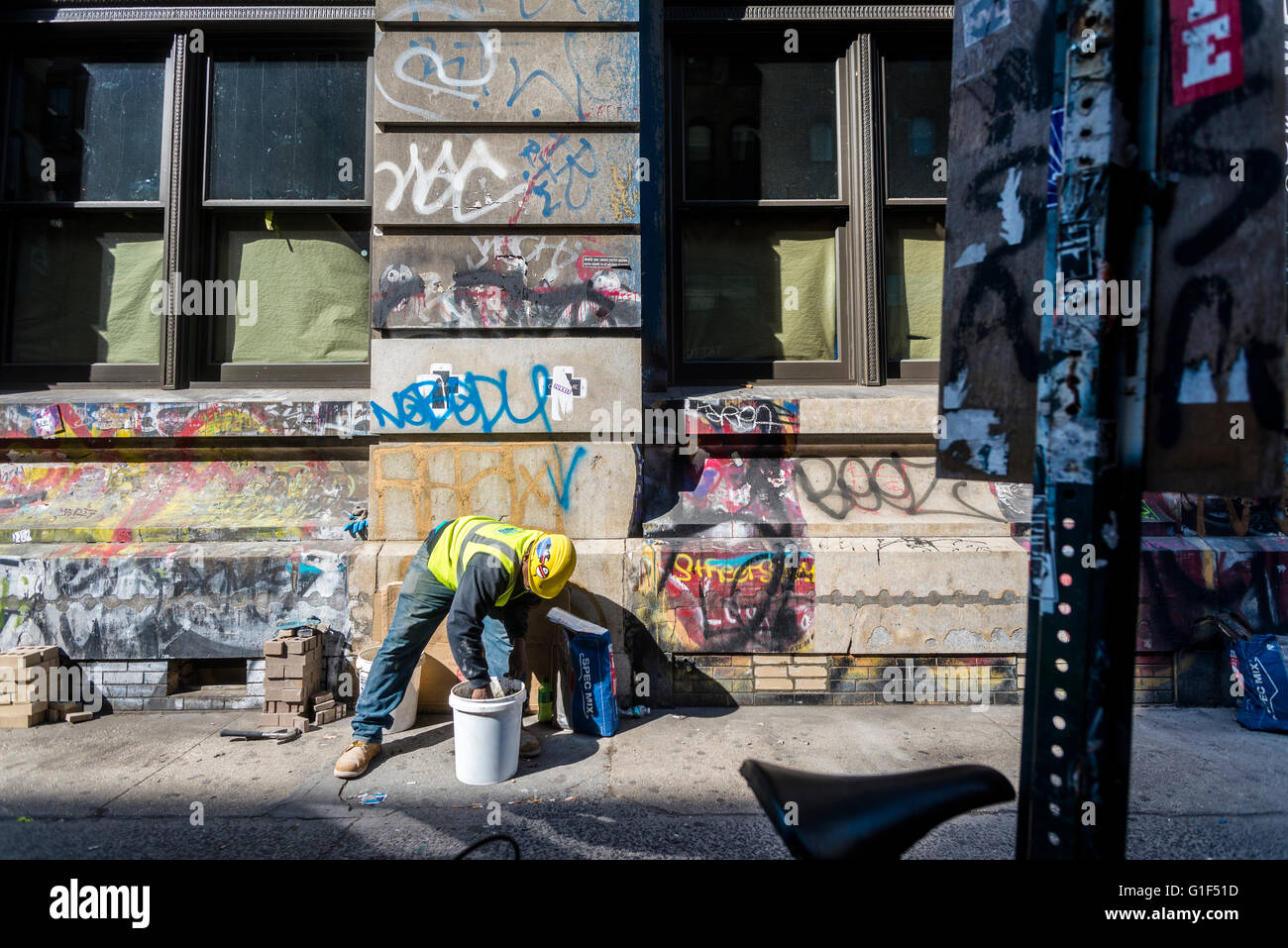 New York, NY - 12 Maggio 2016 - Un operaio si mescola la malta al di fuori della Germania Bank Building vicino il Bowery. L'edificio che sld per 55 milioni di dollari (US) era una volta il studion e casa del fotografo Jay Maisel. ©Stacy Rosenstock Walsh/Alamy Foto Stock