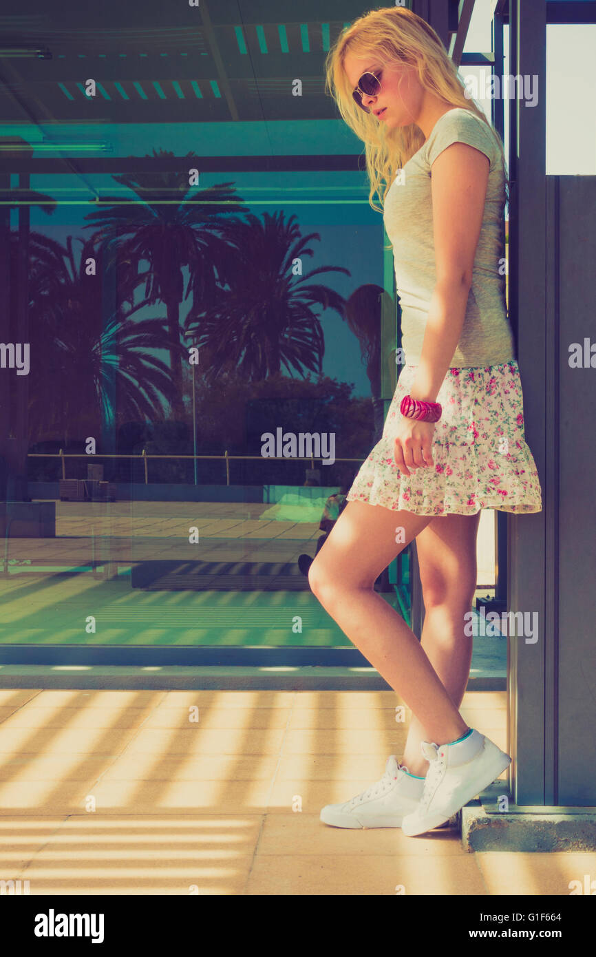 Modello rilasciato. Giovane donna indossa mini gonna in piedi dalla parete. Foto Stock
