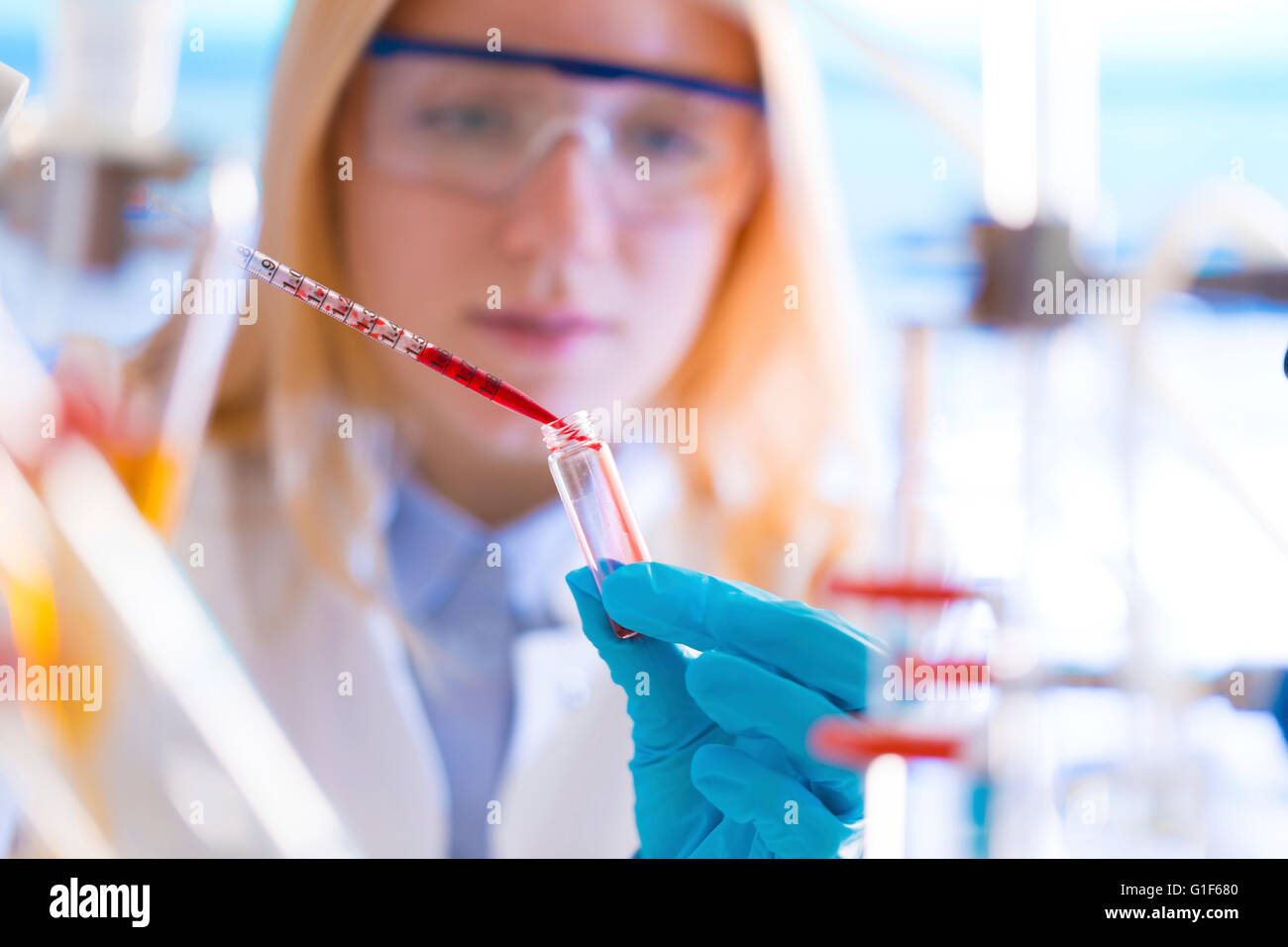 Modello rilasciato. Femmina di tecnico di laboratorio chimico di gocciolamento in provetta con una pipetta. Foto Stock