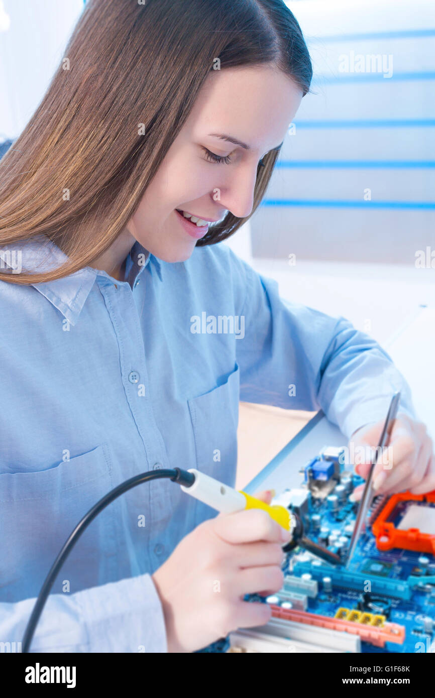 Modello rilasciato. Femmina ingegnere elettrico lavorando su una scheda di circuito. Foto Stock
