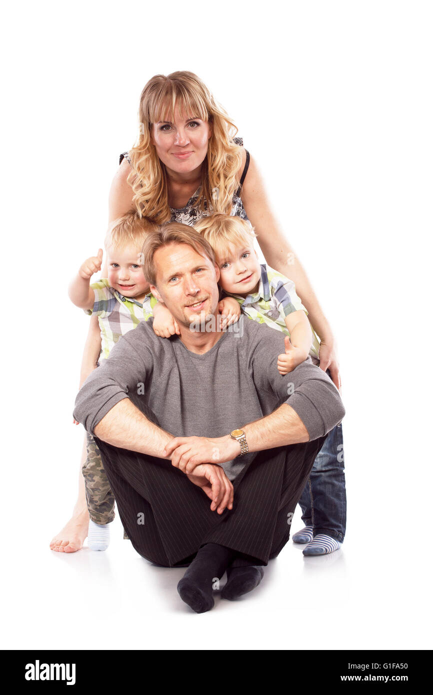 Caucasian sorridenti giovane famiglia con due bambini seduti sul pavimento. Isolato su bianco. Foto Stock