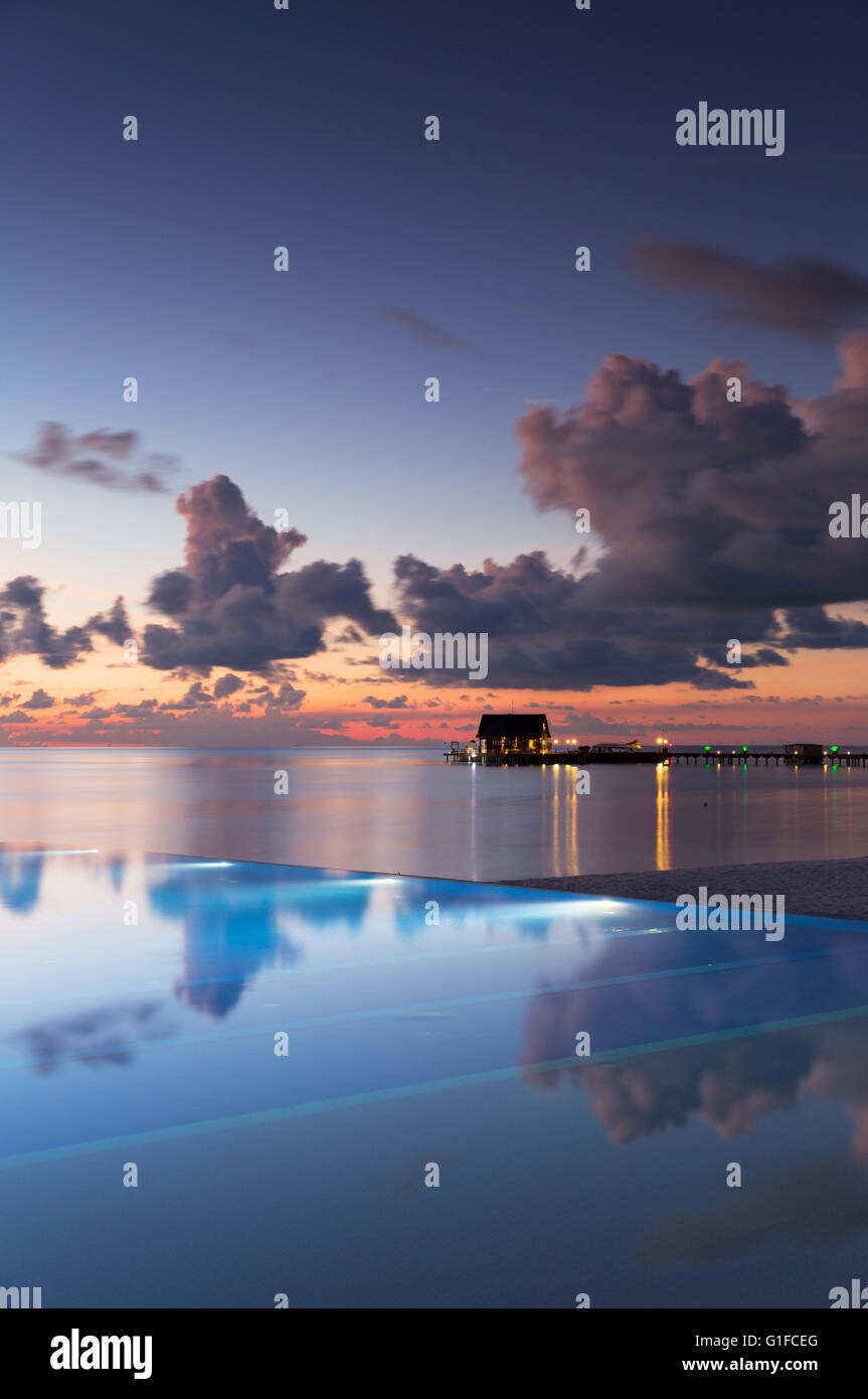 Piscina a sfioro di Olhuveli Beach and Spa Resort al tramonto, South Male Atoll, Kaafu Atoll, Maldive Foto Stock