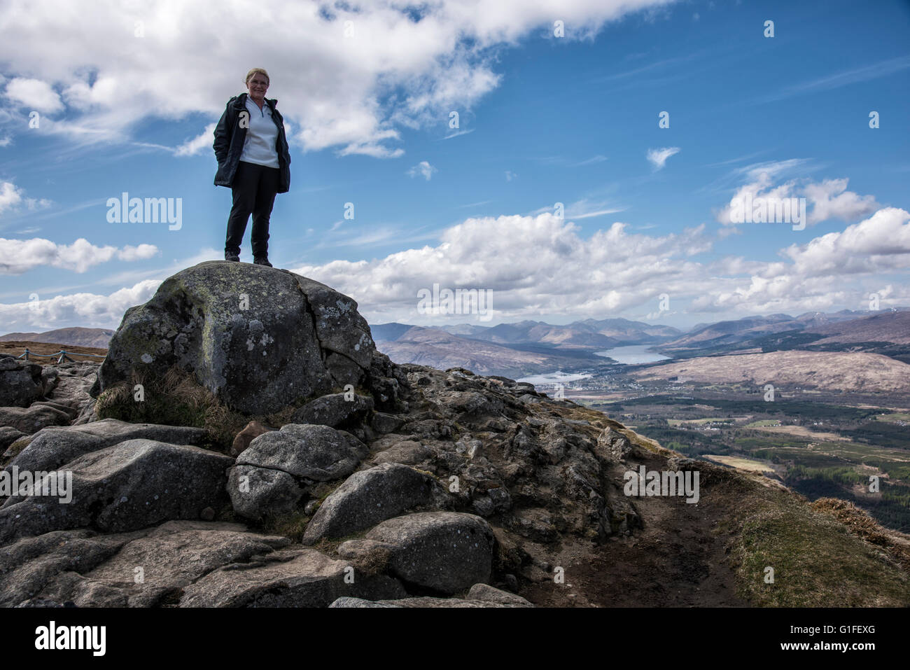 Donna in piedi sulla grande roccia al Sgurr Finniosgaig viewpoint sulla Aonach Mor vicino a Ben Nevis Foto Stock