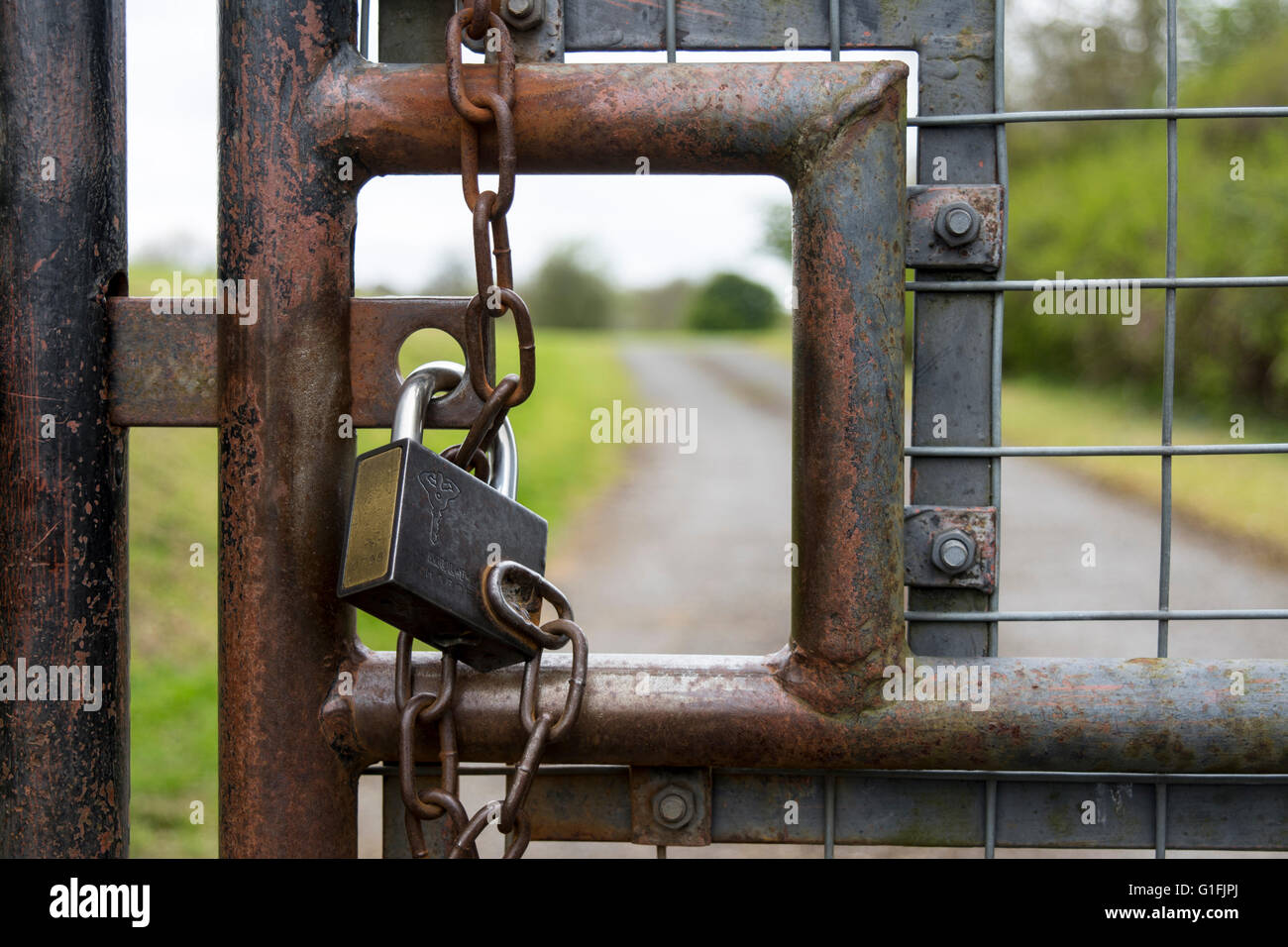 Vista ravvicinata del lucchetto chiuso per esterno in metallo cancelli di sicurezza con catena e ruggine Foto Stock