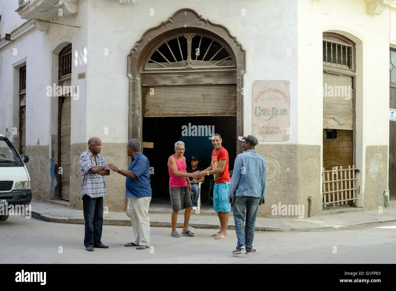 Gli uomini locali scambio degli auguri al di fuori Cafe Alma in Avana Vecchia, Havana, Cuba Foto Stock