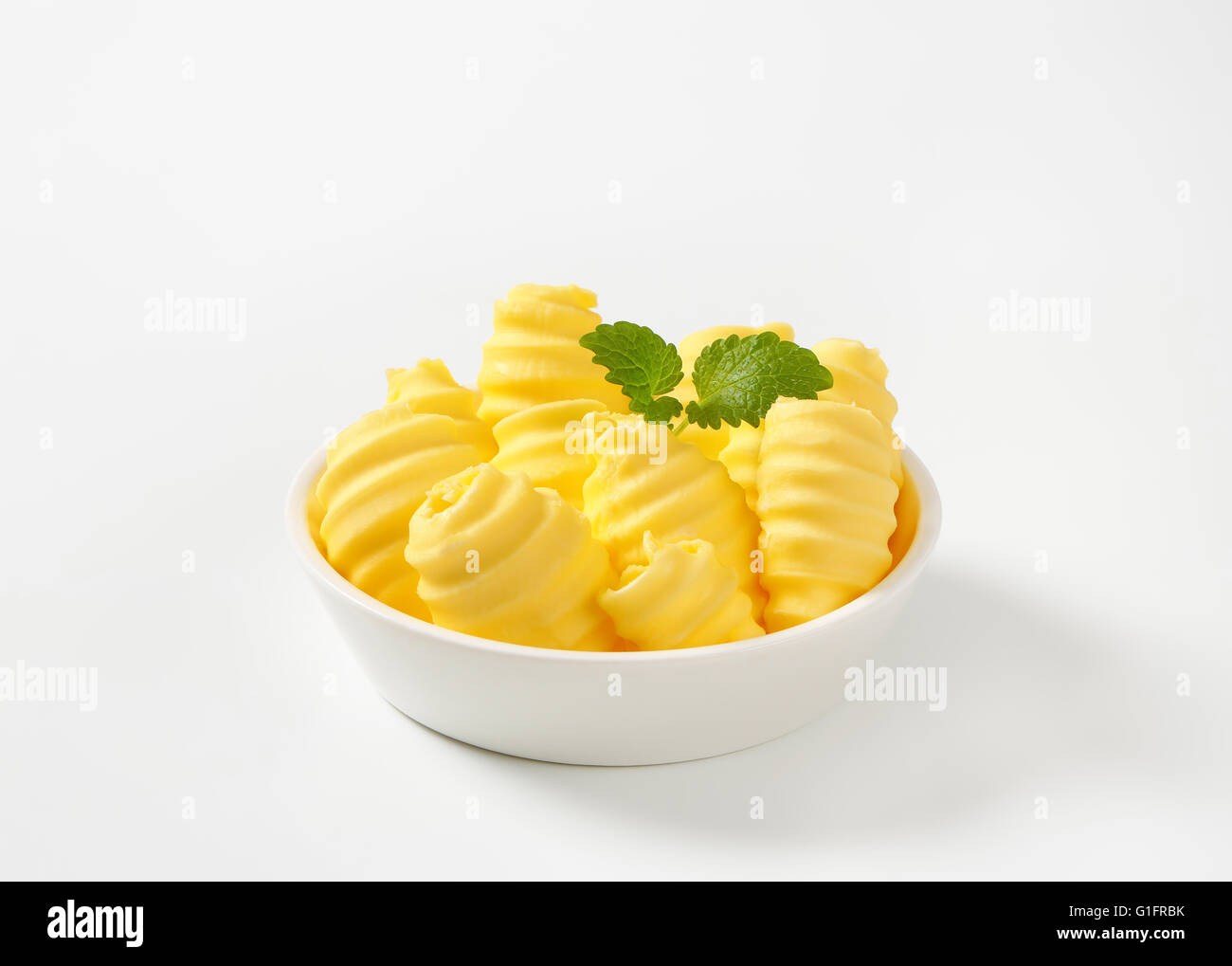 Ciotola del ricciolo di burro con menta su sfondo bianco Foto Stock