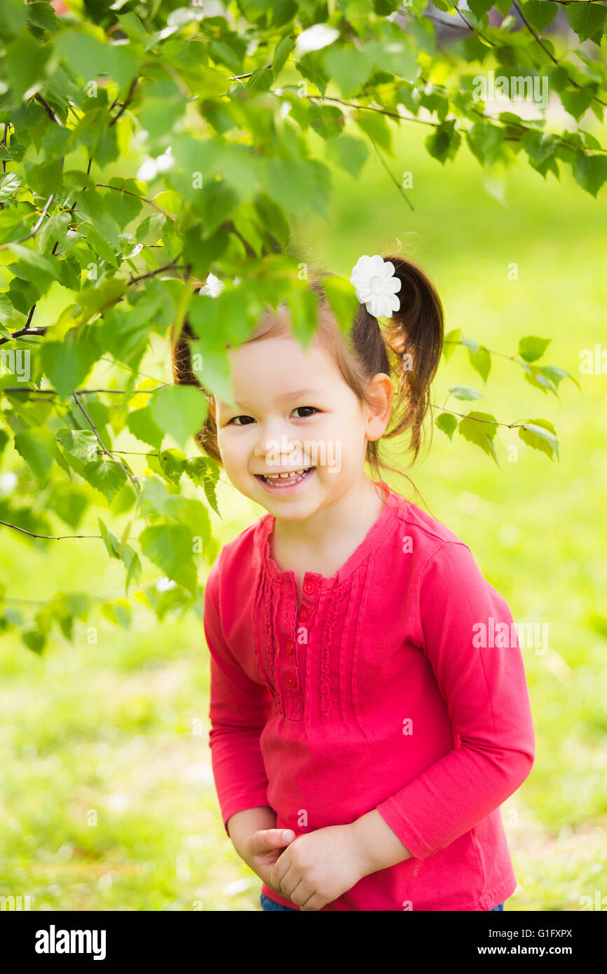 Bambini che giocano a nascondino all'aperto nel parco. Bellissima bambina nascosto dietro un enorme albero in primavera o estate giornata di sole Foto Stock