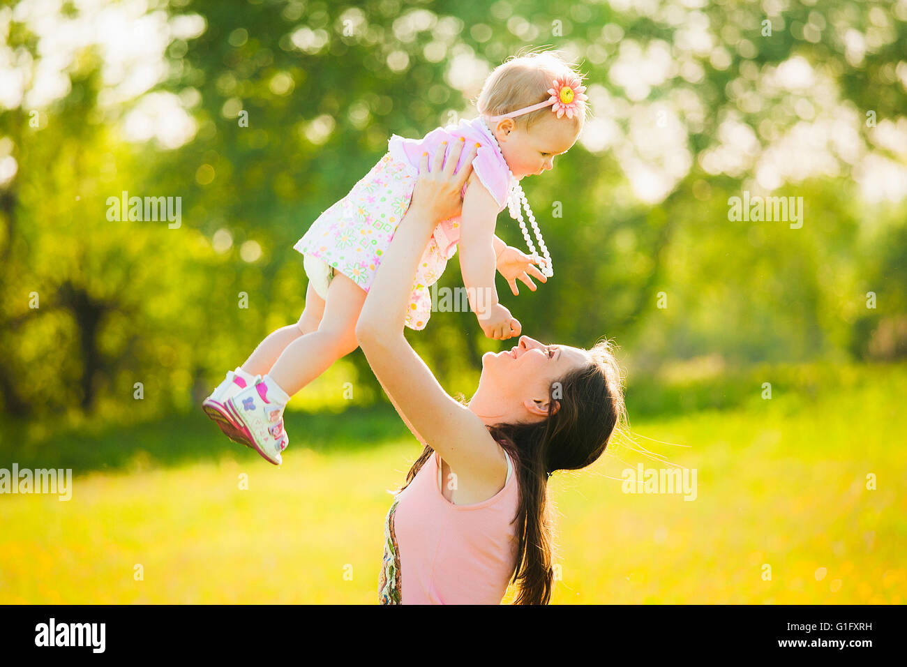 Felice mamma e figlia vestito in abiti rosa suonando insieme alla natura. Sunshine molla o giorno di estate Foto Stock